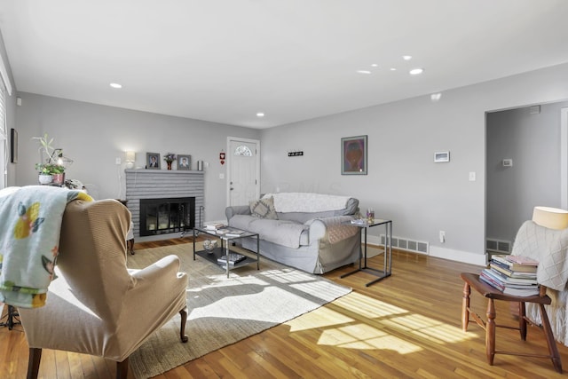 living room with a brick fireplace and light hardwood / wood-style flooring