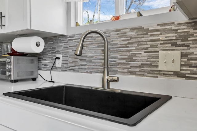 room details featuring tasteful backsplash, white cabinetry, and sink