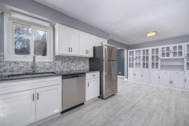 kitchen featuring dark stone countertops, white cabinetry, light hardwood / wood-style flooring, and stainless steel appliances