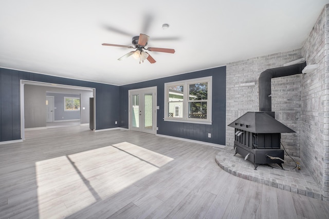 living room with ceiling fan, light wood-type flooring, a wood stove, and french doors