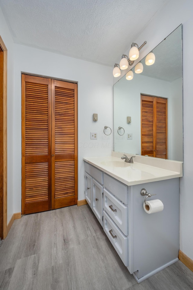 bathroom with hardwood / wood-style floors, vanity, and a textured ceiling