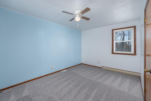 empty room featuring ceiling fan, carpet, wood walls, and a baseboard heating unit