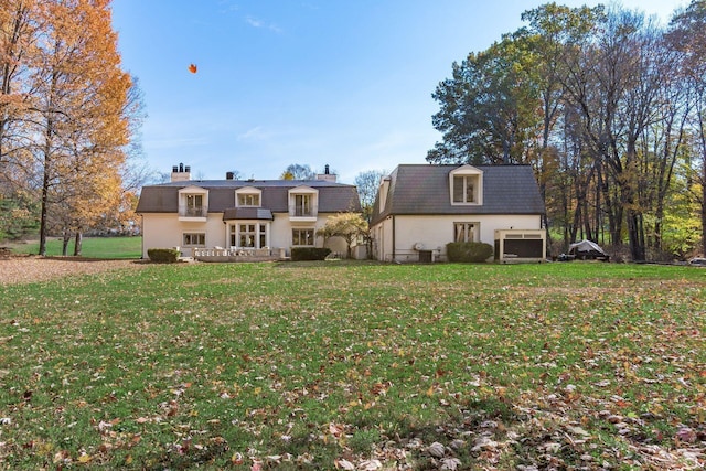 rear view of house featuring a lawn and a garage