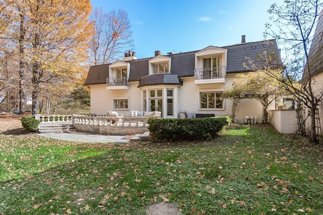 back of house with a lawn, an outdoor living space, a balcony, and a patio