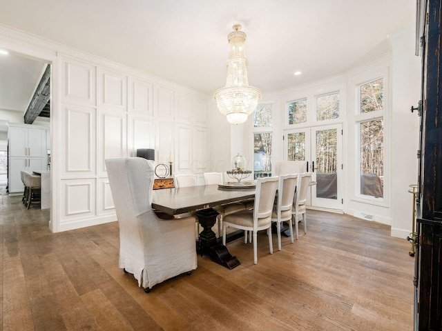 dining area featuring crown molding, french doors, a notable chandelier, and hardwood / wood-style flooring