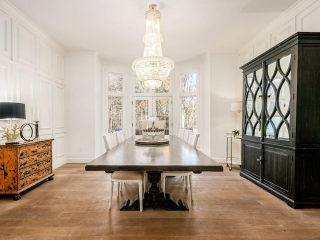 dining room featuring crown molding, light hardwood / wood-style flooring, french doors, and an inviting chandelier