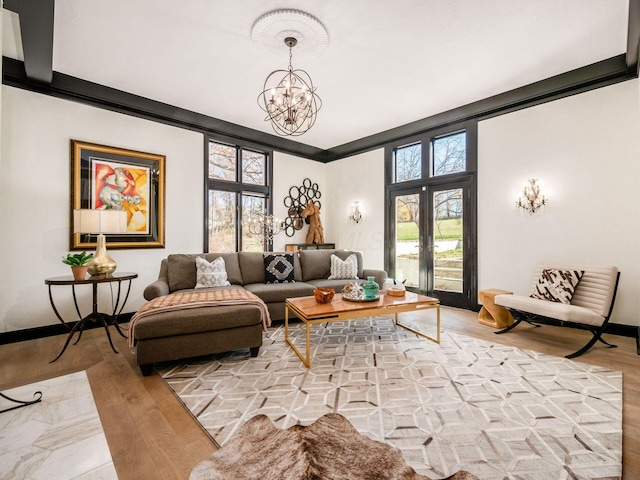 sitting room featuring french doors, light hardwood / wood-style floors, crown molding, and a notable chandelier