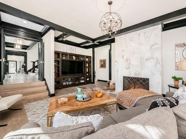 living room featuring a high end fireplace, light hardwood / wood-style flooring, beamed ceiling, and a chandelier