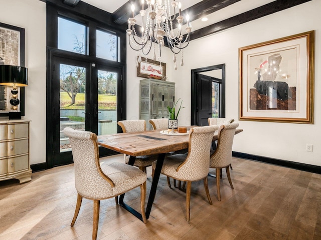 dining space with a high ceiling, french doors, beam ceiling, a notable chandelier, and light hardwood / wood-style floors