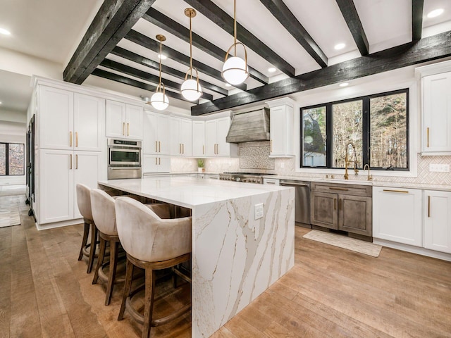 kitchen with white cabinets, sink, decorative light fixtures, a kitchen island, and stainless steel appliances