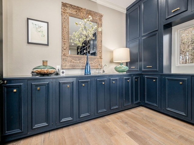 bar with blue cabinetry, light wood-type flooring, and ornamental molding