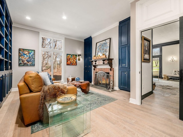 sitting room featuring a brick fireplace, ornamental molding, and light wood-type flooring