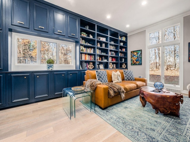 living area with a wealth of natural light, crown molding, and light wood-type flooring