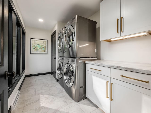 laundry area featuring cabinets, stacked washer and clothes dryer, and a baseboard heating unit