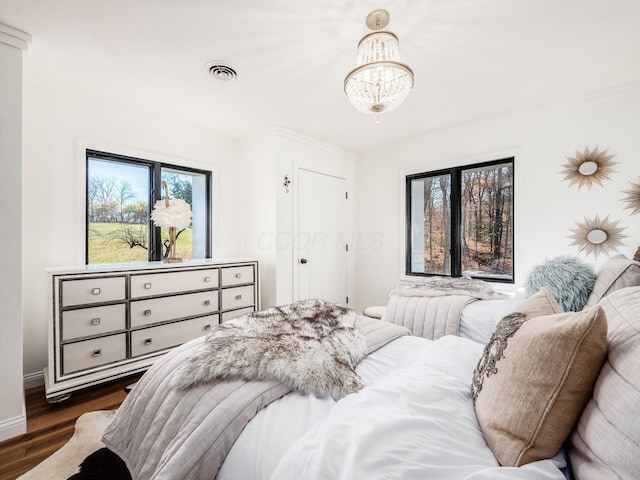 bedroom with a notable chandelier, dark hardwood / wood-style floors, and crown molding