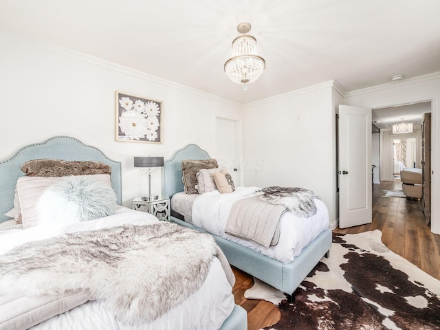 bedroom featuring wood-type flooring, an inviting chandelier, and ornamental molding