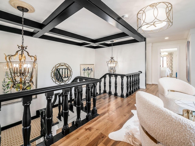 hall with wood-type flooring, a notable chandelier, coffered ceiling, and beam ceiling