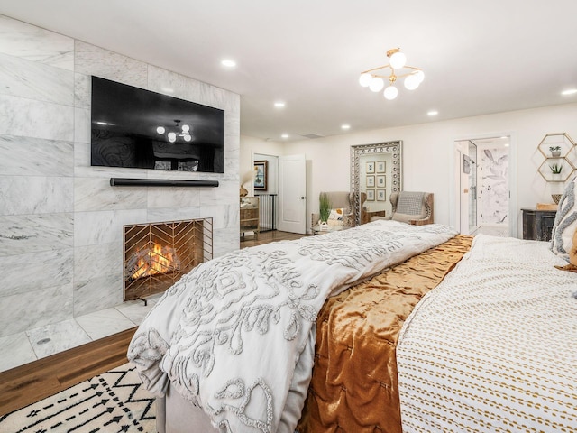 bedroom with a chandelier, light hardwood / wood-style flooring, tile walls, and a tiled fireplace