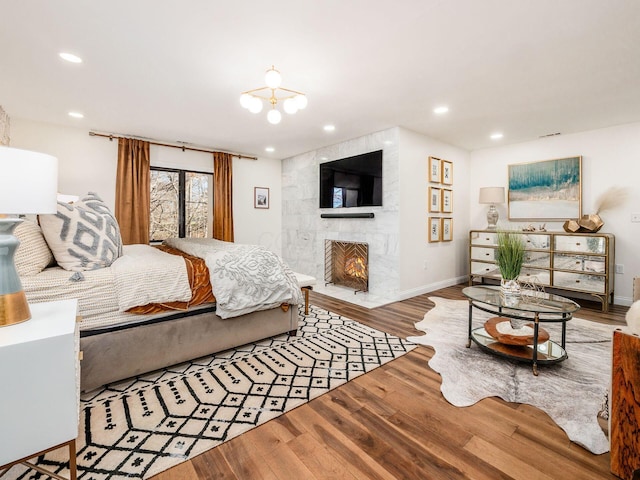 bedroom featuring hardwood / wood-style flooring, a fireplace, and a chandelier