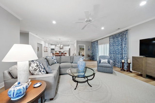 living room featuring ceiling fan with notable chandelier, light wood-type flooring, and ornamental molding