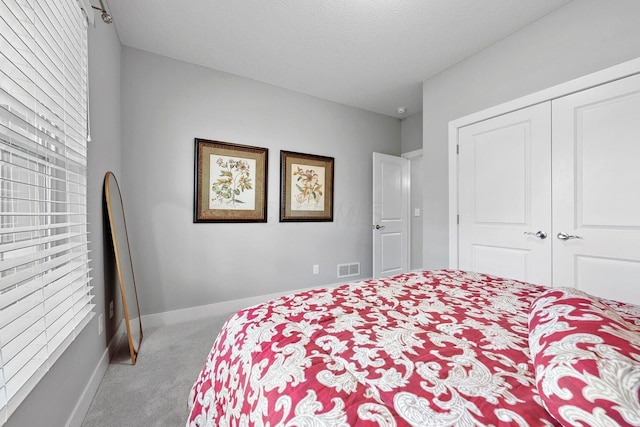 bedroom featuring light colored carpet, a textured ceiling, and a closet