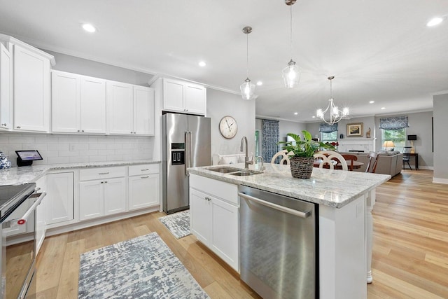 kitchen with stainless steel appliances, white cabinetry, hanging light fixtures, and light hardwood / wood-style floors