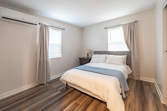 bedroom featuring dark hardwood / wood-style floors, a wall unit AC, and multiple windows