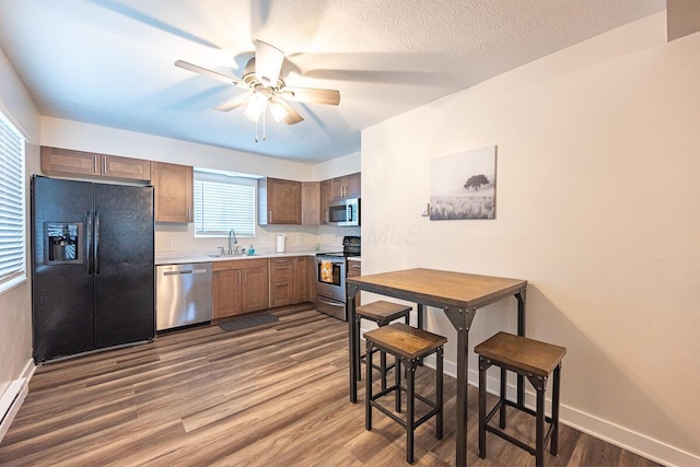 kitchen with sink, ceiling fan, a textured ceiling, wood-type flooring, and stainless steel appliances