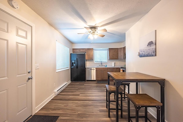 kitchen with appliances with stainless steel finishes, a textured ceiling, ceiling fan, dark wood-type flooring, and a baseboard radiator