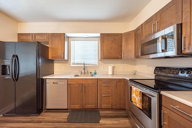 kitchen featuring a textured ceiling, stainless steel appliances, dark hardwood / wood-style floors, and sink