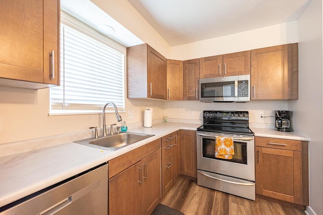 kitchen with hardwood / wood-style floors, sink, stainless steel appliances, and a textured ceiling