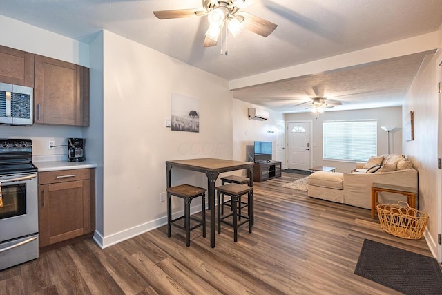 kitchen with an AC wall unit, dark hardwood / wood-style floors, ceiling fan, a textured ceiling, and appliances with stainless steel finishes