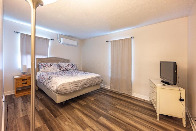 bedroom featuring dark hardwood / wood-style flooring, a textured ceiling, and a wall mounted AC