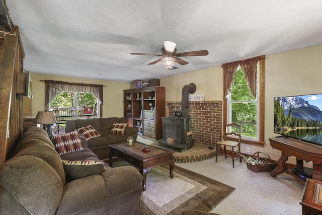 living room featuring a wood stove, carpet, a textured ceiling, and a ceiling fan