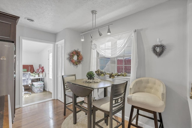 dining space with light hardwood / wood-style floors and a textured ceiling