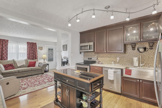 kitchen with light wood-type flooring, dark brown cabinets, a textured ceiling, stainless steel appliances, and sink