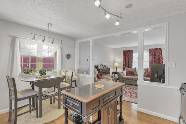 kitchen featuring light hardwood / wood-style flooring, a textured ceiling, decorative light fixtures, dark brown cabinets, and decorative columns