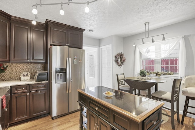 kitchen with stainless steel refrigerator with ice dispenser, dark brown cabinetry, a textured ceiling, and light hardwood / wood-style flooring