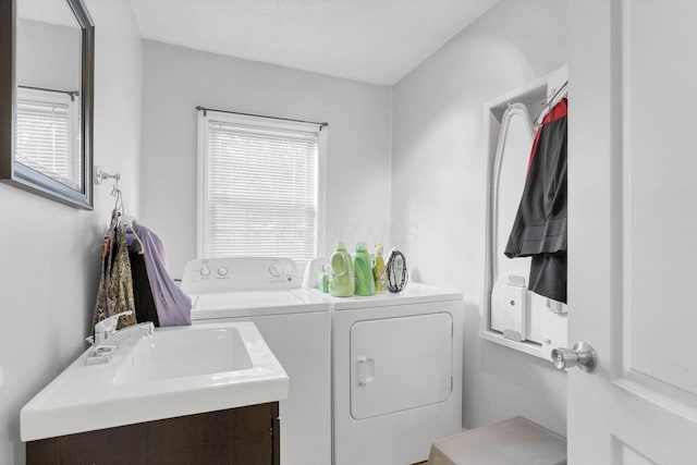 washroom with washer and dryer, a textured ceiling, and sink