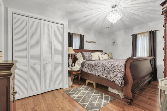 bedroom with a closet, an inviting chandelier, a textured ceiling, and hardwood / wood-style flooring