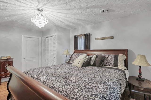 bedroom with a closet, a chandelier, a textured ceiling, and hardwood / wood-style flooring