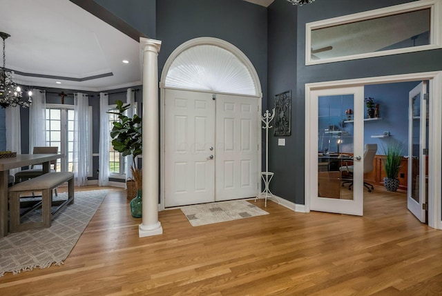 foyer featuring french doors, ornate columns, and wood-type flooring