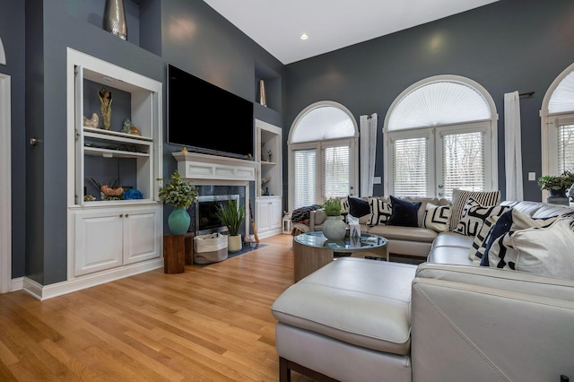 living room with a fireplace, built in shelves, and light hardwood / wood-style floors