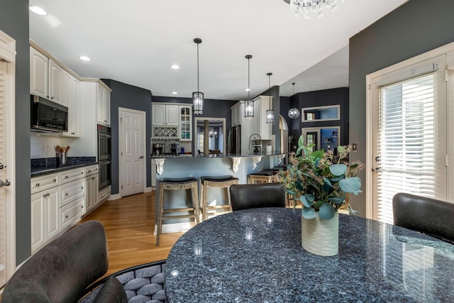 kitchen with appliances with stainless steel finishes, tasteful backsplash, hanging light fixtures, and hardwood / wood-style floors