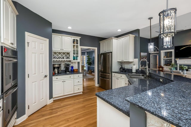 kitchen featuring sink, light hardwood / wood-style flooring, a notable chandelier, decorative light fixtures, and appliances with stainless steel finishes