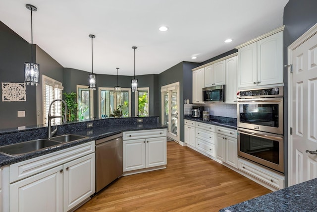 kitchen featuring decorative light fixtures, stainless steel appliances, light hardwood / wood-style flooring, and sink