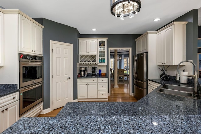 kitchen with backsplash, an inviting chandelier, sink, hardwood / wood-style flooring, and stainless steel appliances