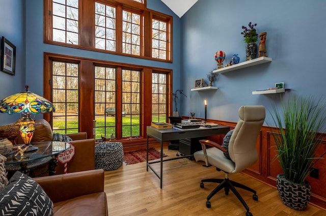 home office with high vaulted ceiling and light hardwood / wood-style floors