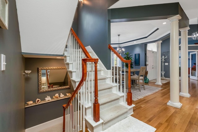 stairs featuring a tray ceiling, hardwood / wood-style floors, and a chandelier