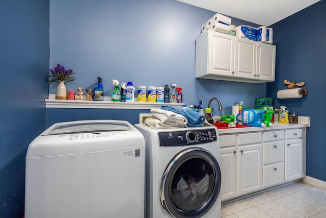 laundry area with washing machine and clothes dryer, sink, light tile patterned floors, and cabinets